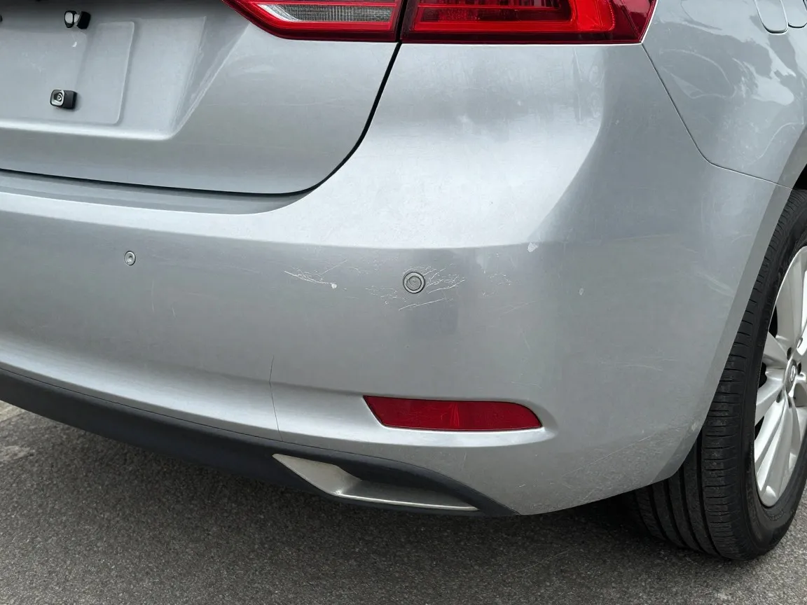 Scuffed rear bumper cover with scratches and white paint transfer; the plastic is not cracked